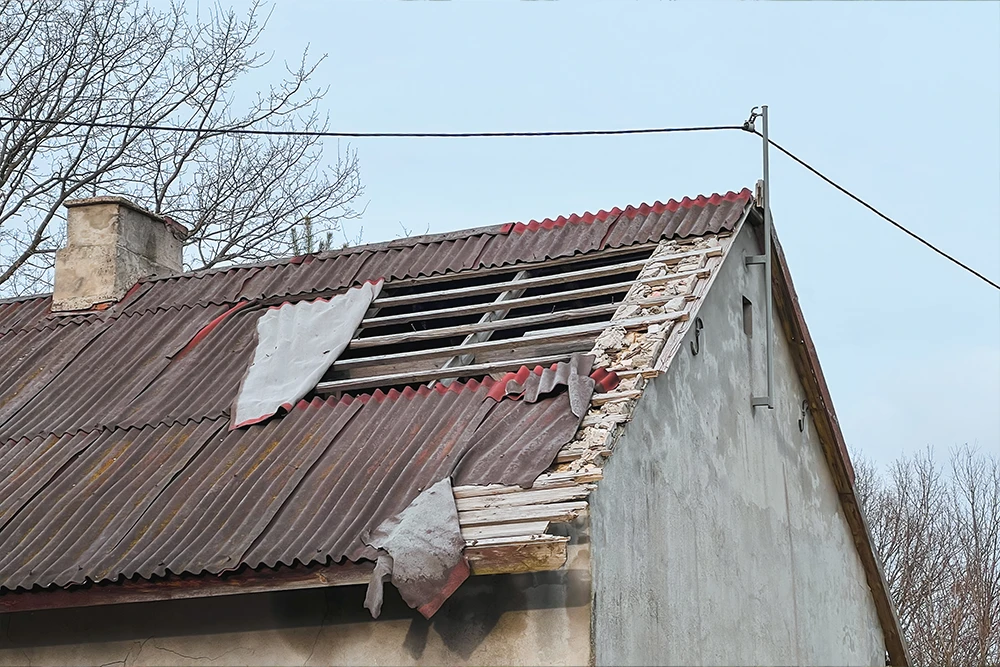 Sturmbeschädigtes Ziegeldach mit herausgerissenen Dachziegeln und freigelegten Holzlatten nach Unwetter in der Steiermark
